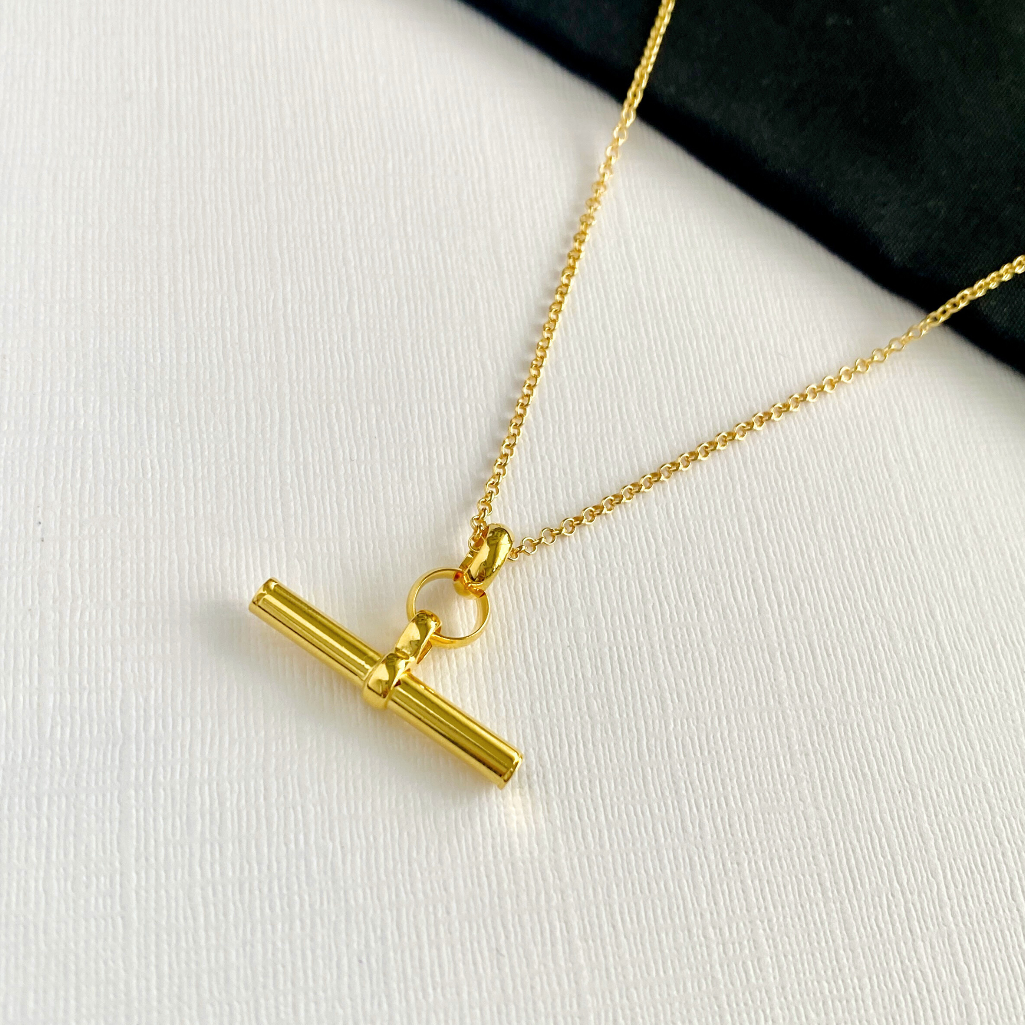 On trend gold T bar necklace on background to show the high-quality materials and contemporary necklace design. KookyTwo.