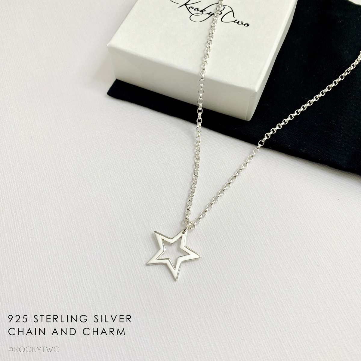 Sterling silver open star charm necklace on white background with gift box.