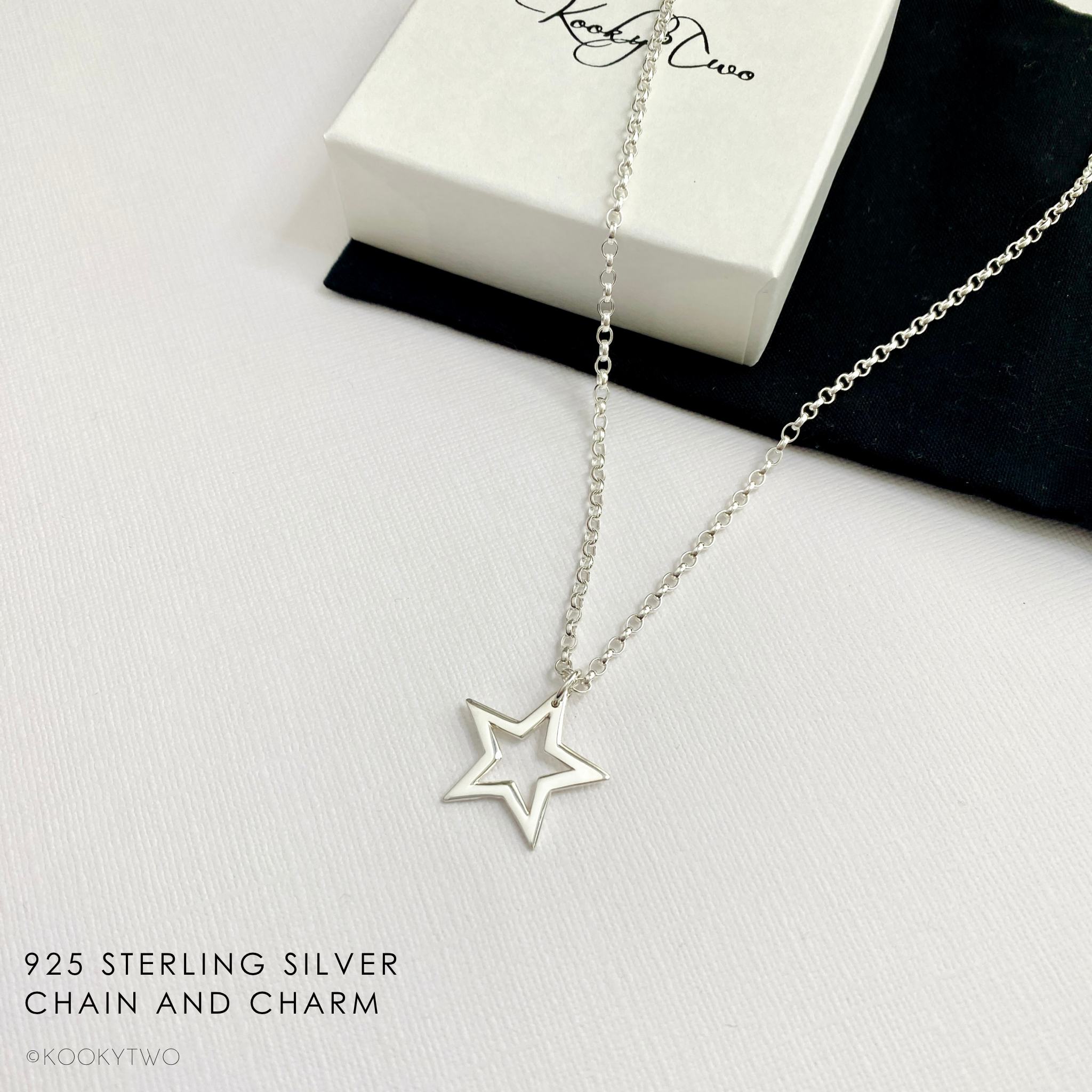 Sterling silver open star charm necklace on white background with gift box.