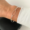 Eternity bangle in sterling silver on a wrist with a white top.