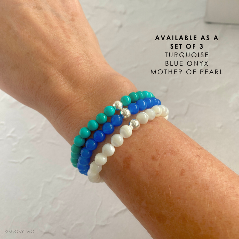 A stunning set of three handmade gemstone bracelets featuring turquoise, blue onyx, and mother of pearl, perfect for stacking or wearing solo.