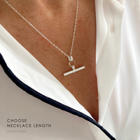 Sterling silver t-bar-charm necklace on a person wearing a white blouse, with the words choose a necklace length.