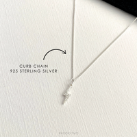 Sterling silver necklace with lightning bolt charm on curb chain on a white background.