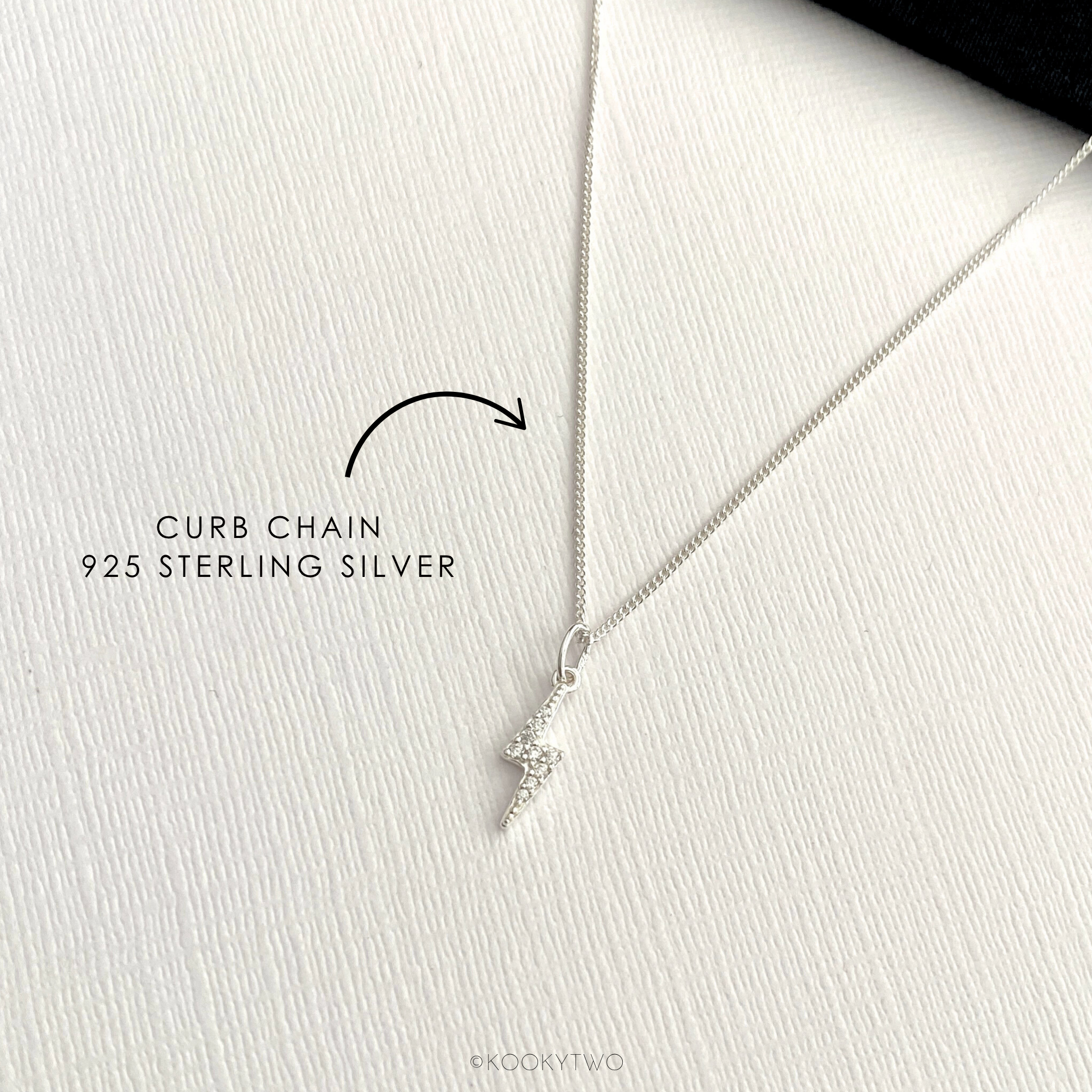 Sterling silver necklace with lightning bolt charm on curb chain on a white background.