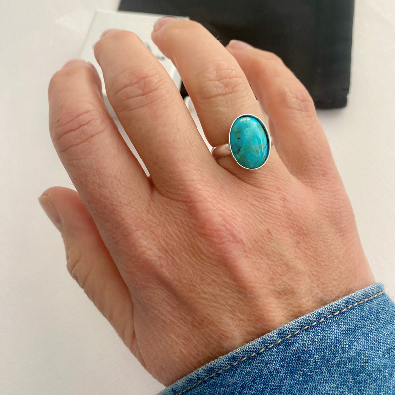Hand wearing a turquoise ring on a white background