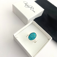 Oval Turquoise gemstone ring in a white box.