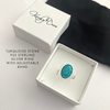 Turquoise stone ring with adjustable band in a white box on a light background