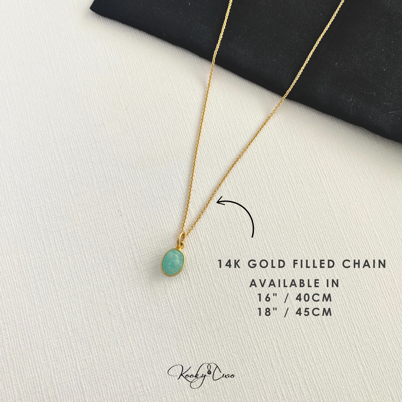 Gold necklace with a green pendant on a white surface, labeled '14K Gold Filled Chain'.