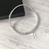 Minimalist sterling silver bracelet with polished beads and a star charm, ideal for stacking or wearing solo. KookyTwo.