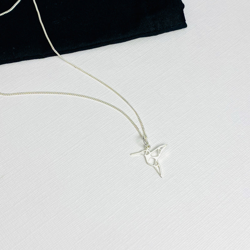 Bird charm necklace with hummingbird pendant on chain.