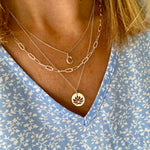 Necklace layering look with initial charm necklace, paperclip chain necklace and lotus flower charm necklace.
