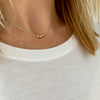 Dainty silver necklace with three shiny gold beads that move freely along the chain. Kooky Two.