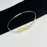 Silver bangle with gold infinity charm. Stylish bracelet for women.