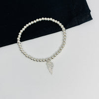 Minimalist sterling silver bracelet with shiny silver beads and an angel wing charm, ideal for stacking or wearing solo. KookyTwo.