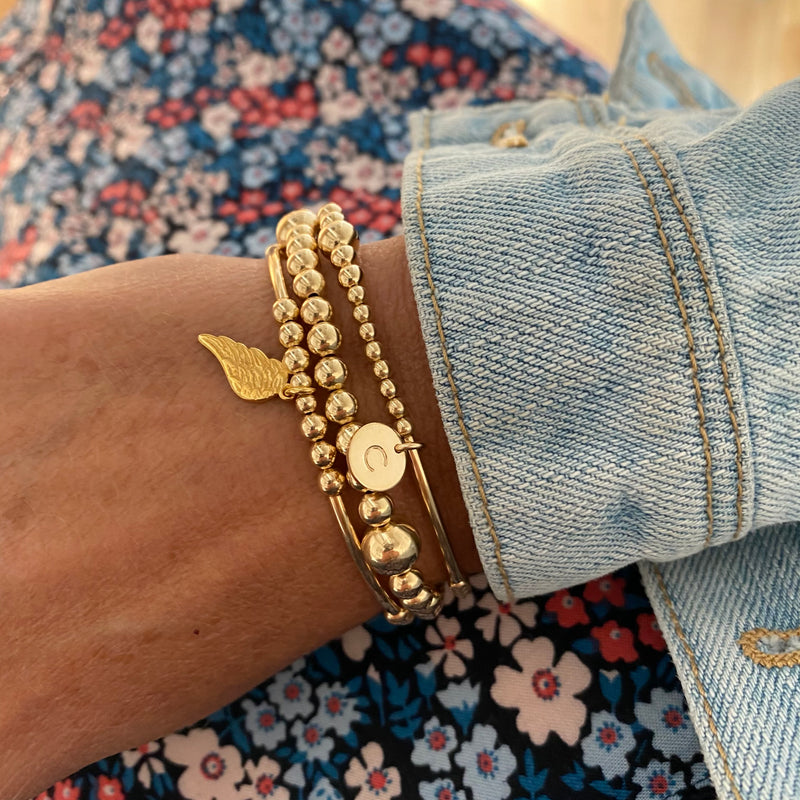 Gold stacking bracelet set with personalised disc and angel wing charm in gold.