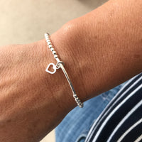 A beautiful sterling silver bead bracelet with a heart charm, worn on a wrist for a timeless and meaningful look. KookyTwo.