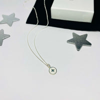 Pole star necklace with white detail on charm. 