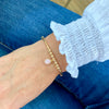 Gold bead bracelet with pink opal gemstone charm.