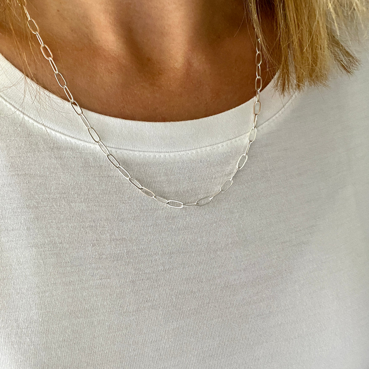 Sterling silver paperclip necklace with long links for a statement look, shown on a lady wearing a white t-shirt, made by KookyTwo Jewellery.
