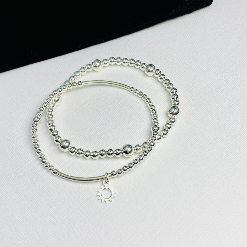 Bracelet stacking set gift for her. Summer jewellery style with sun charm bracelet and shiny silver bead bracelet. Summer outfit accessories.